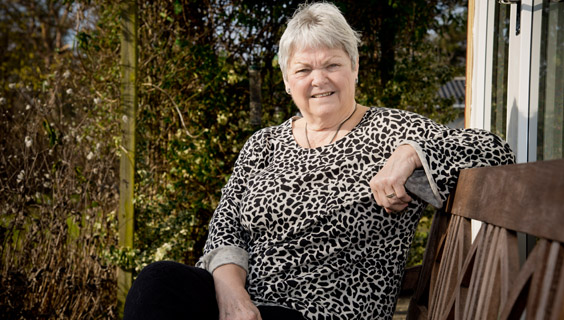 Kvinde i 60'erne sidder på en havebænk
